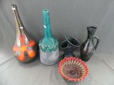 cinq vases différents posés sur une surface grise