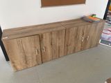 un meuble TV en bois dans une pièce où la télévision est accrochée au mur