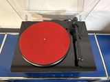 a turntable with a red disc on it on a blue table