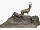 sculpture en bronze représentant deux cerfs sur un rocher, sur fond blanc