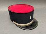 une image représentant un chapeau orné d'un ruban rouge et noir