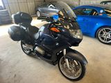 une moto noire garée dans un garage à côté d'une voiture bleue