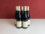 three bottles of wine sit on a table in front of a red wall