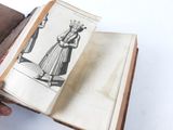 someone is holding an old book with a drawing of a woman in a dress