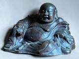 a small statue of a laughing buddha sitting on a table