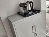a coffee pot on top of a cabinet in the corner of a room