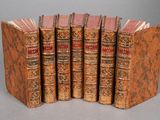 six vieux livres alignés en rang sur une surface grise