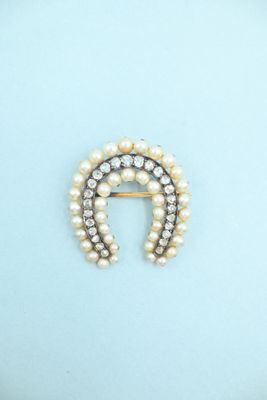 a close up of a pearl and diamond broochle on a blue background