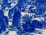 a blue and white plate with a picture of a group of people on it