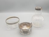 trois petits bocaux en verre avec des couvercles argentés, posés sur une surface blanche