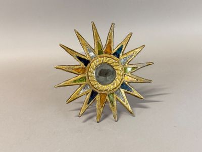 une image représentant un soleil rayonnant en or, orné de pierres vertes et bleues