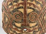 a close up of a wooden mask on a stand