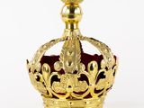gold crown on a white background with a red velvet cushion