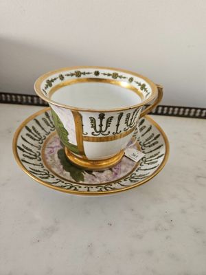 tea cup and saucer with gold trim on a marble table