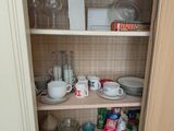 un placard sur lequel sont posés de nombreux plats et tasses