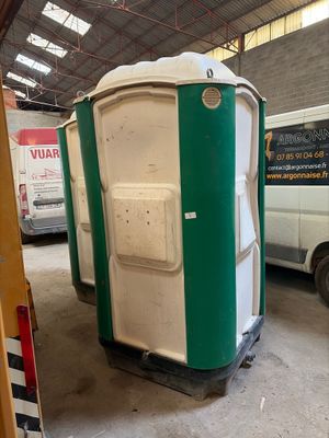 des toilettes portables vertes et blanches installées dans un garage