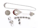 a lot of silver jewelry on a white surface
