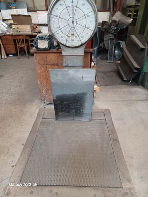 une grande balance métallique posée par terre dans un atelier