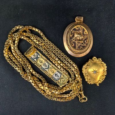 deux colliers en or et une montre posés sur un fond noir
