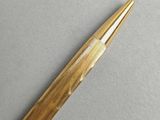 an image of a pen with a gold tip on a gray surface