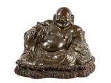 statue d'un Bouddha souriant, assis sur un coussin posé sur une surface blanche