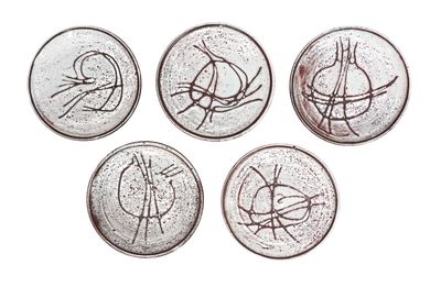 four coins with a drawing of a bird on them on a white surface