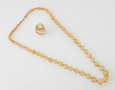 a close up of a necklace and a ring on a white surface