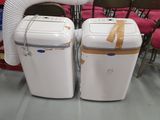 pair of white portable air conditioners sitting in a room with red chairs