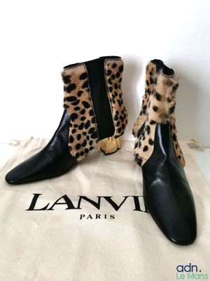 une paire de bottes noires à imprimé léopard posées sur un sac blanc