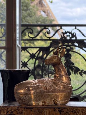 a statue of a deer on a table in front of a window