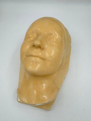 une sculpture jaune représentant une tête d'homme sur une surface blanche