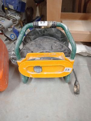 une roue jaune à laquelle est raccordé un tuyau, dans un garage