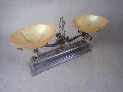 une balance posée sur une table, avec deux récipients dessus