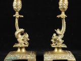 paire de bougeoirs anciens en laiton ornés de têtes de dragon sur leurs socles