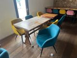 brightly colored chairs sit around a wooden table in a coffee shop