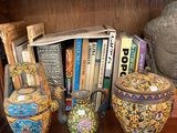 many vases and books on a shelf in a room
