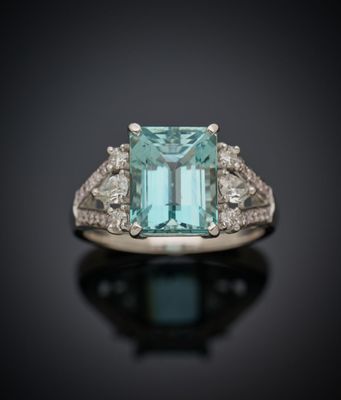 un gros plan d'une bague sertie d'une émeraude entourée de diamants