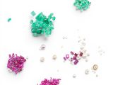 some green and pink beads and pearls on a white surface