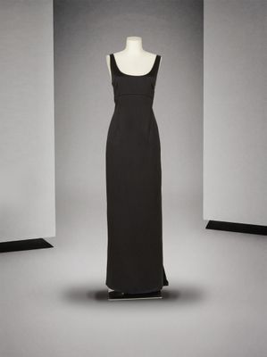 une robe noire sur un mannequin posé sur un socle, dans une pièce