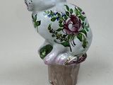 a figurine of a cat sitting on top of a cupcake