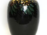 a black vase with yellow and green designs on it