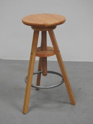 tabouret en bois avec des pieds en métal et une assise en bois, posé sur un sol en béton