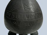 a black vase with a bird on it sitting on a stand