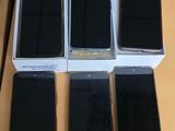 several cell phones are sitting on a table with a person standing next to them