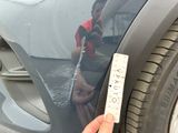 a person holding a measuring tape next to a car
