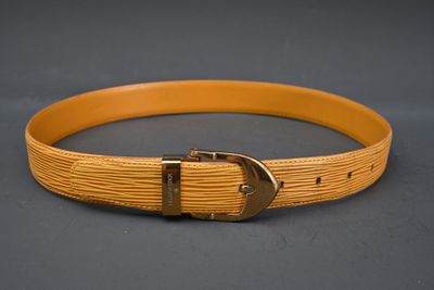 Gros plan sur une ceinture dotée d'une boucle métallique, posée sur une surface grise