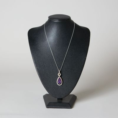 pendentif violet en forme de larme, monté sur un collier noir de type « mannequin », sur fond blanc