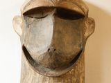une sculpture en bois représentant le visage d'un homme, posée sur une table