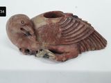 a small vase with a bird on it on a white surface