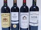 quatre bouteilles de vin sont alignées sur une surface blanche